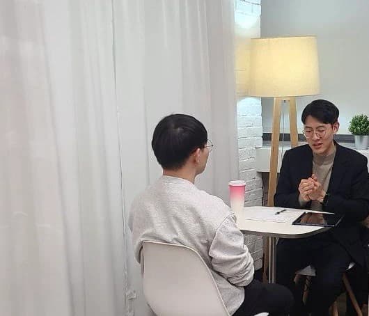 작은 테이블을 사이에 두고 마주 앉아 대화하는 두 사람